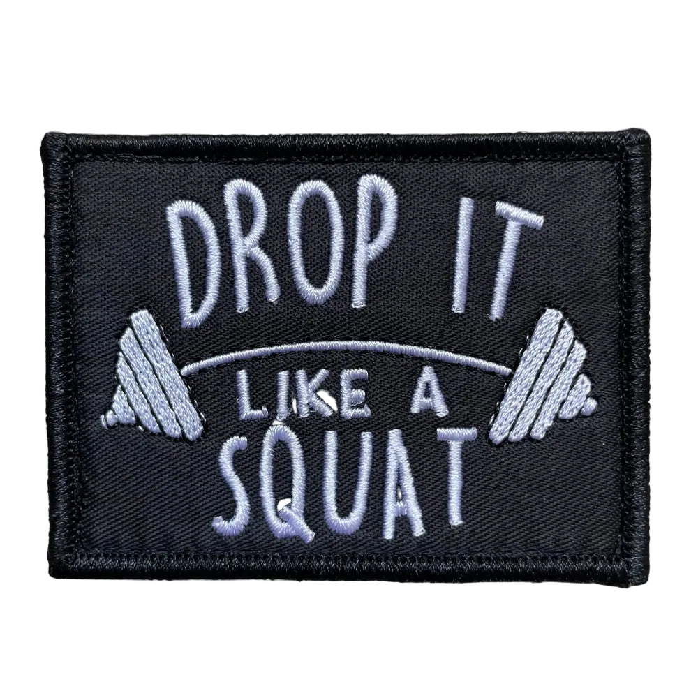 A black velcro patch with the text 'DROP IT LIKE A SQUAT' in white letters.